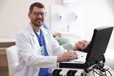 Photo of Sonographer with ultrasound machine and woman waiting for examination in clinic, selective focus