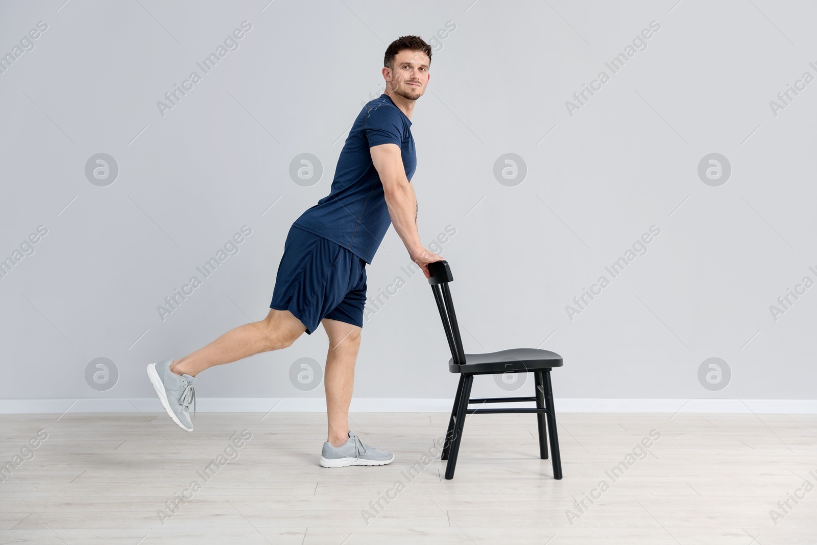 Handsome man exercising with chair at home Photo of Handsome man exercising with chair at home