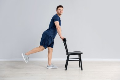 Photo of Handsome man exercising with chair at home