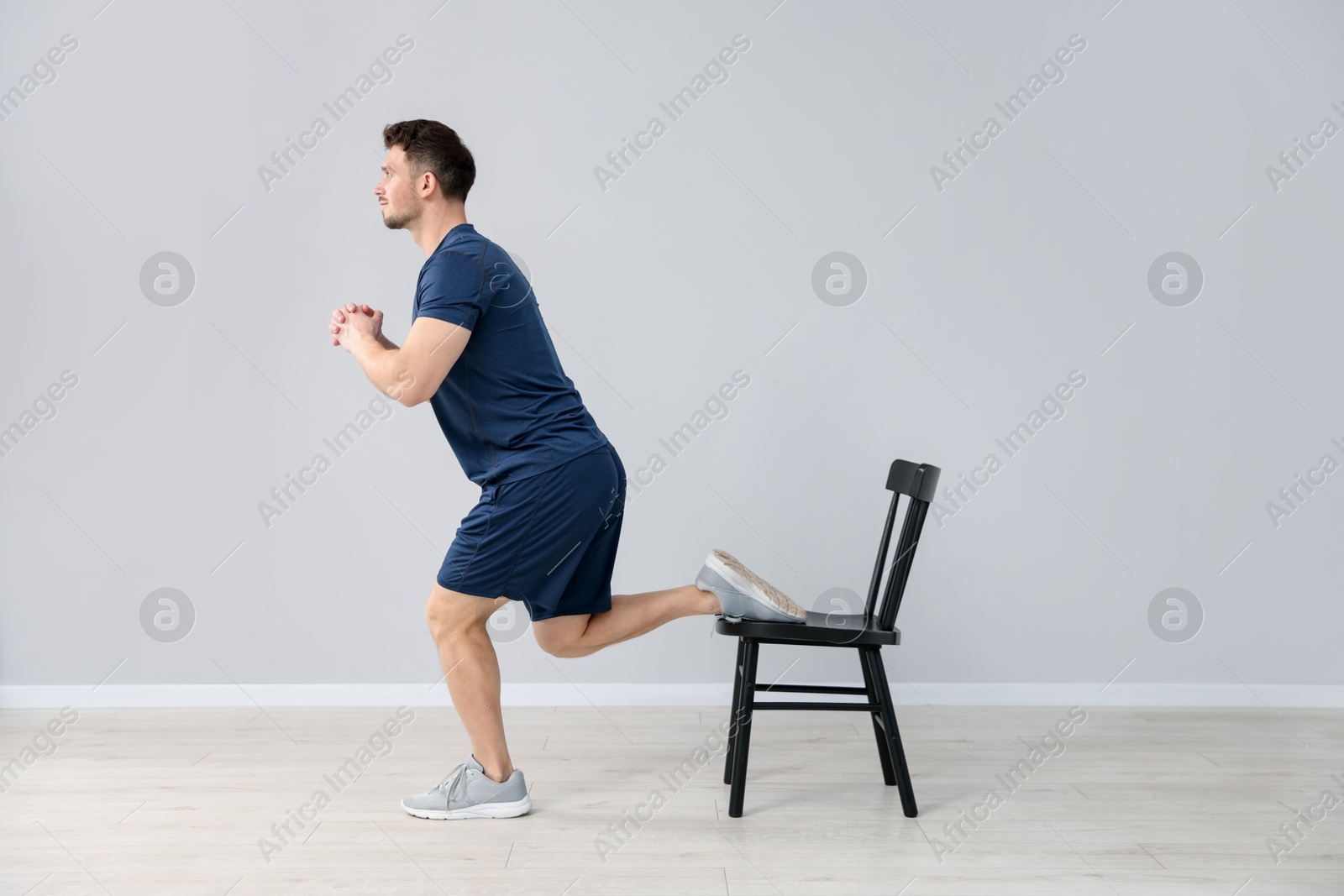 Handsome man exercising with chair at home Photo of Handsome man exercising with chair at home