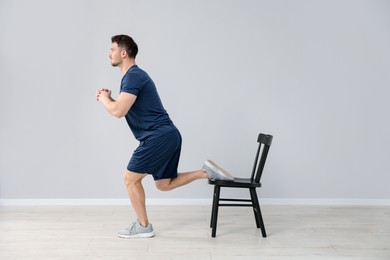 Photo of Handsome man exercising with chair at home