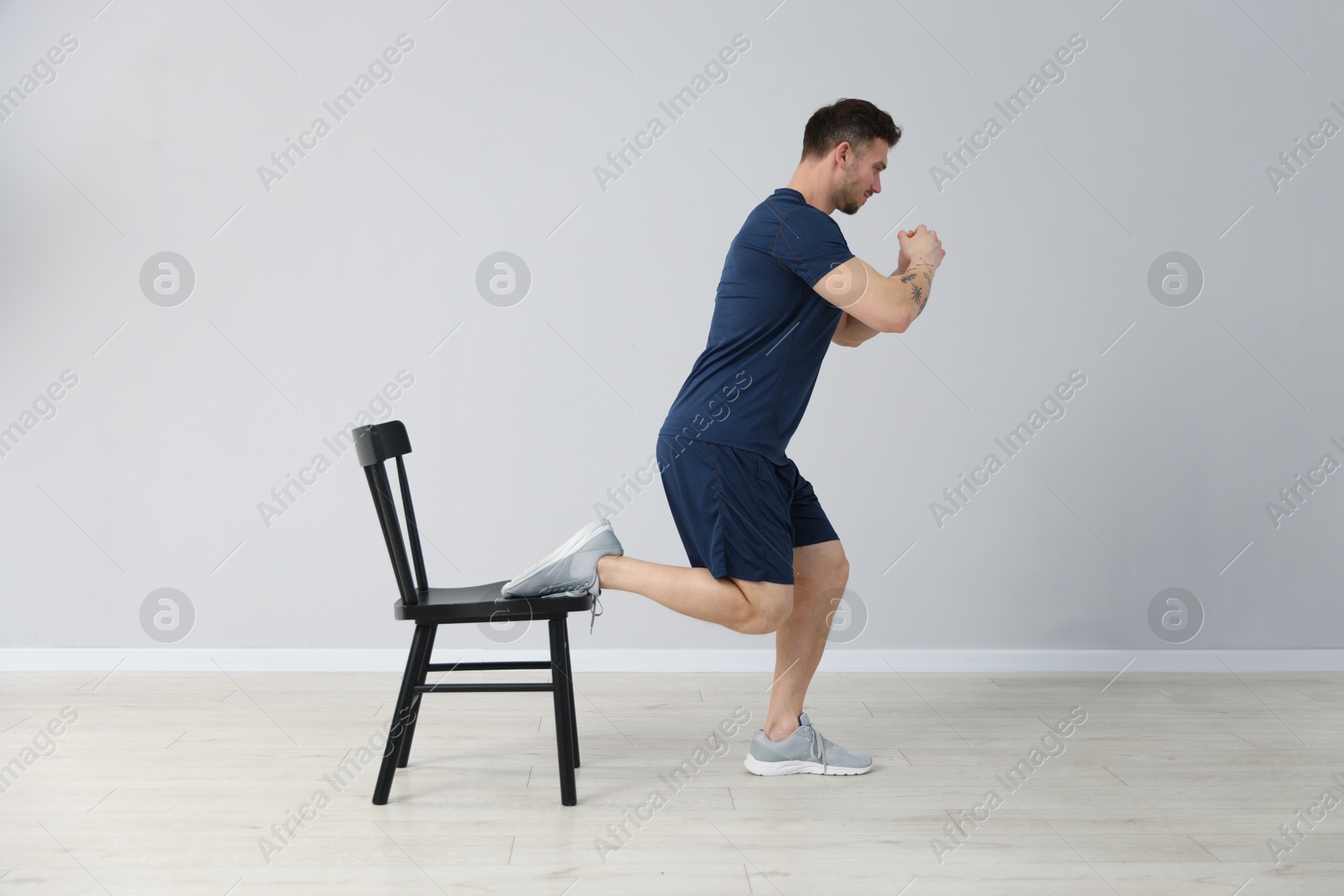 Handsome man exercising with chair at home Photo of Handsome man exercising with chair at home