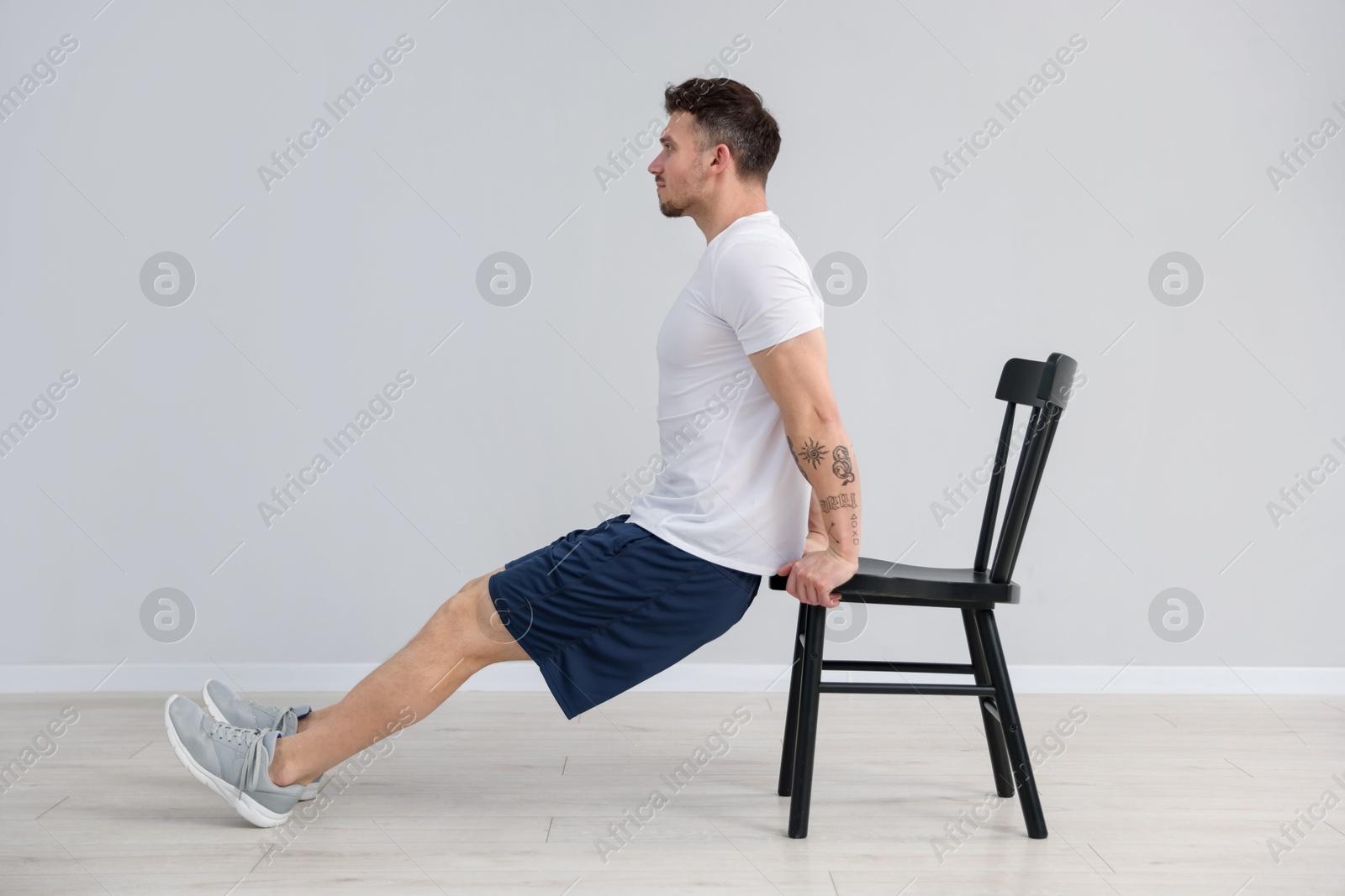 Handsome man exercising with chair at home Photo of Handsome man exercising with chair at home
