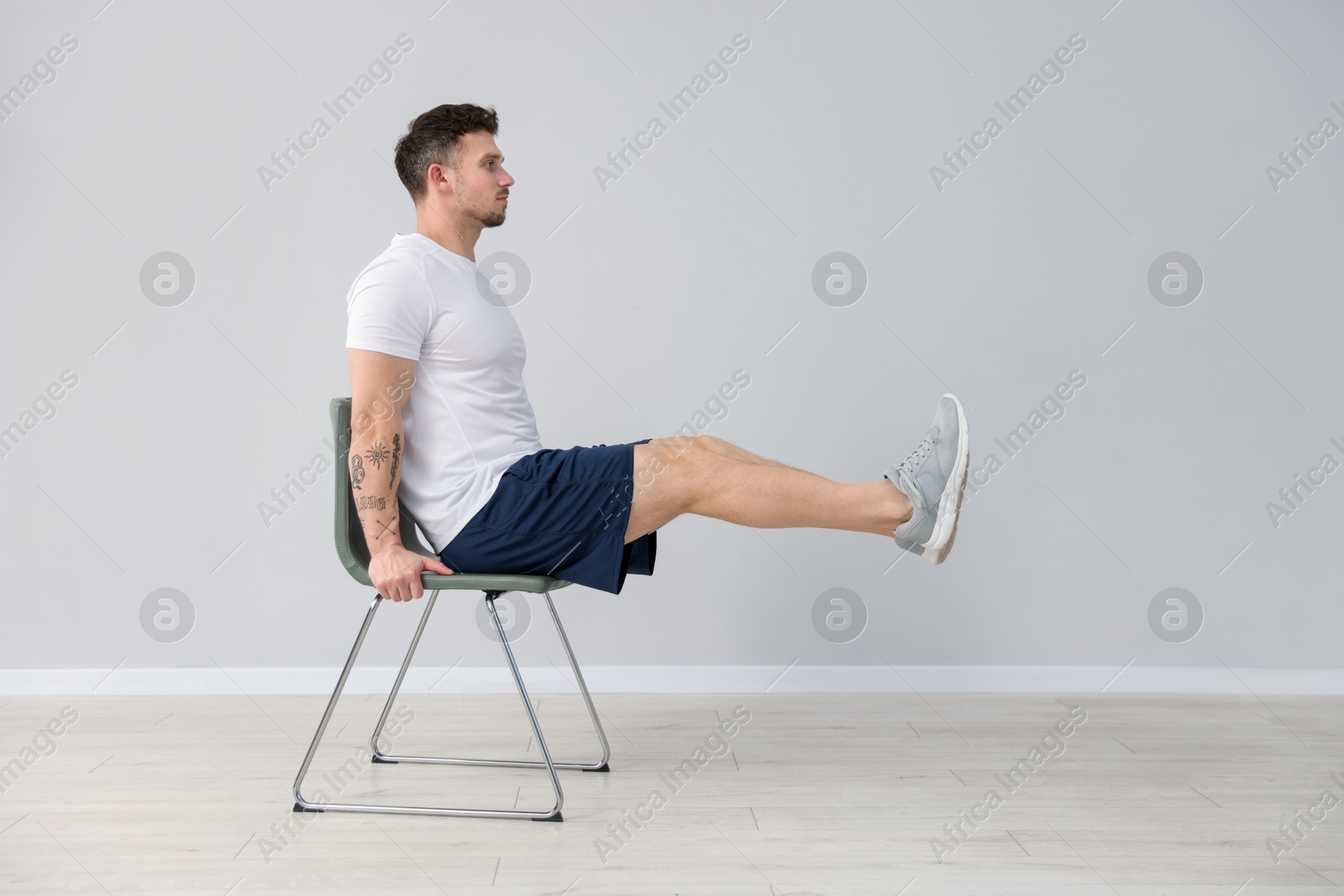 Handsome man exercising with chair at home Photo of Handsome man exercising with chair at home