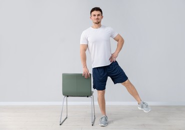 Photo of Handsome man exercising with chair at home