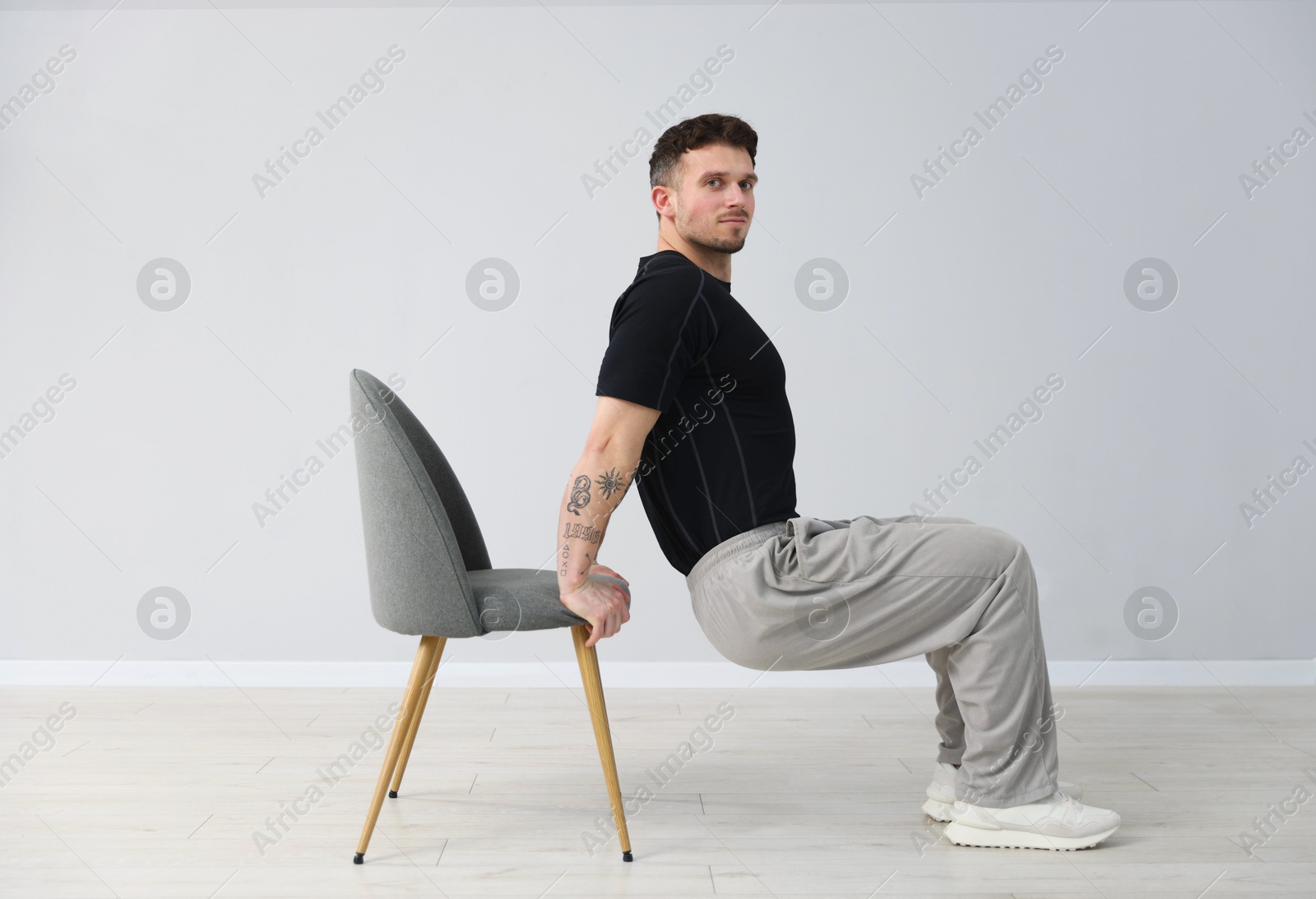 Handsome man exercising with chair at home Photo of Handsome man exercising with chair at home