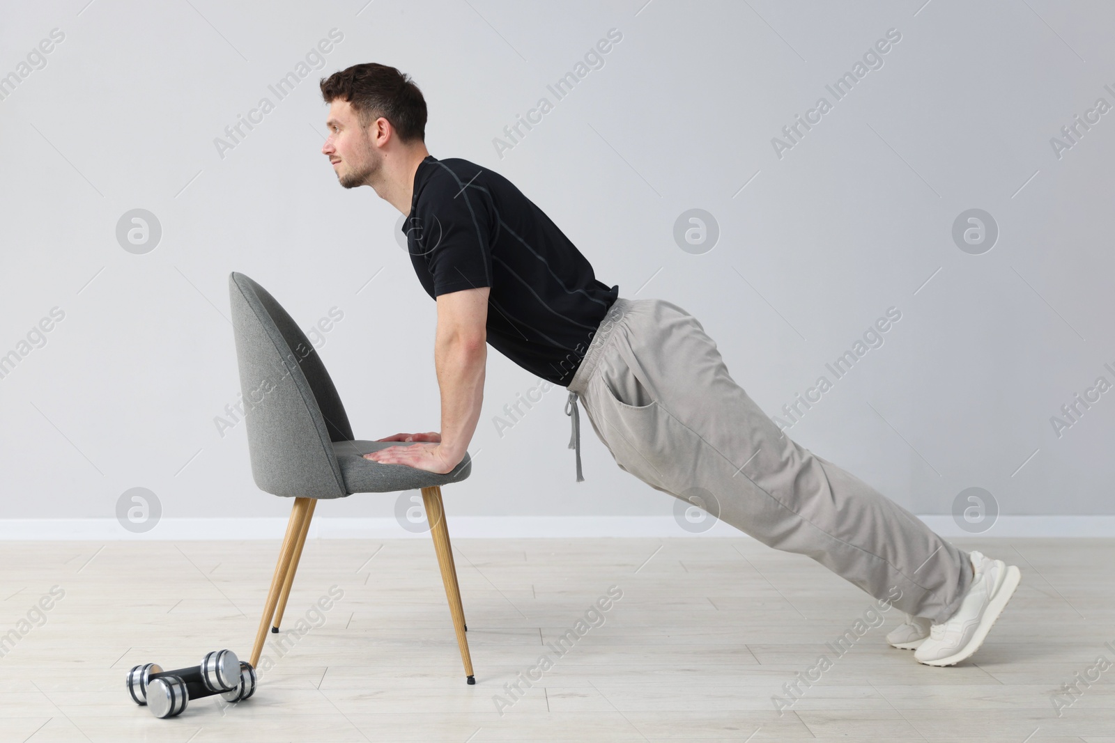 Handsome man exercising with chair at home Photo of Handsome man exercising with chair at home