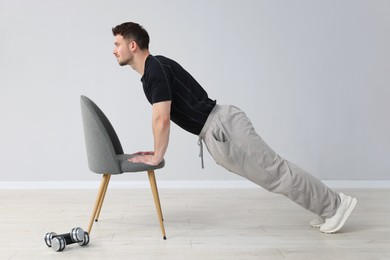 Photo of Handsome man exercising with chair at home