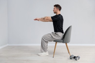 Photo of Handsome man exercising with chair at home