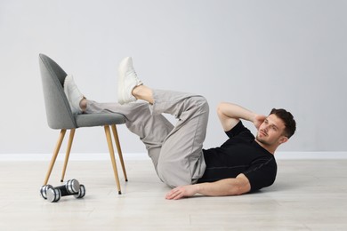 Photo of Handsome man exercising with chair at home