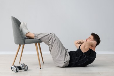 Photo of Handsome man exercising with chair at home