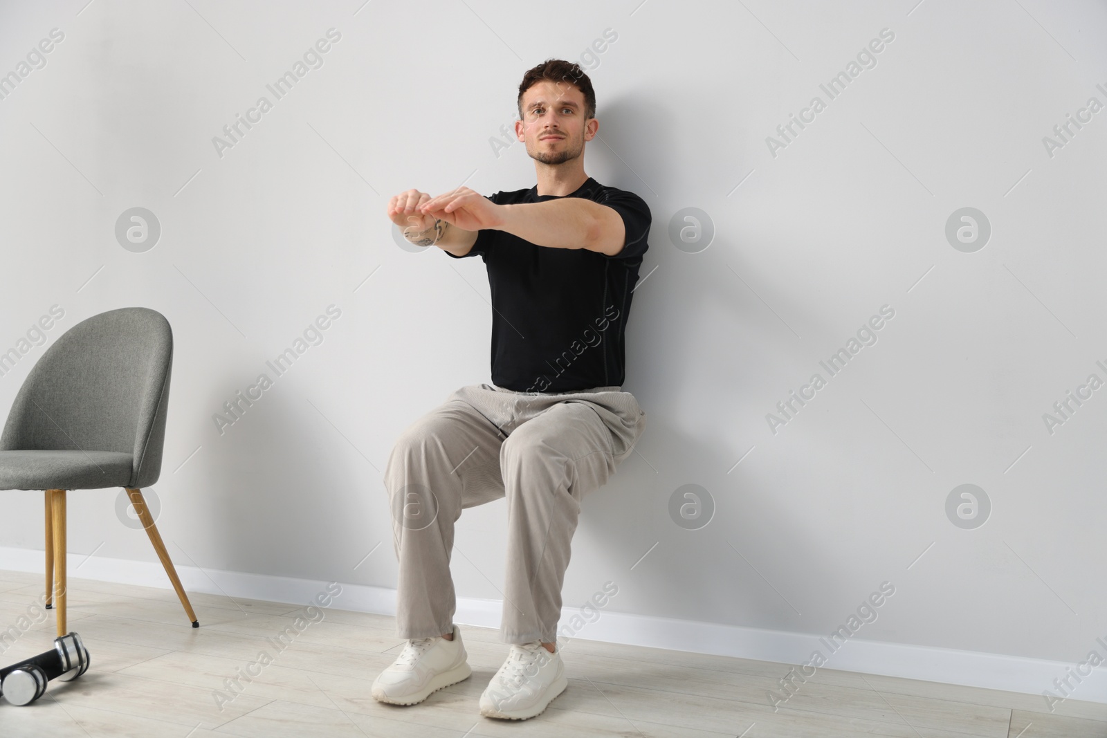 Handsome man exercising near light grey wall indoors Photo of Handsome man exercising near light grey wall indoors