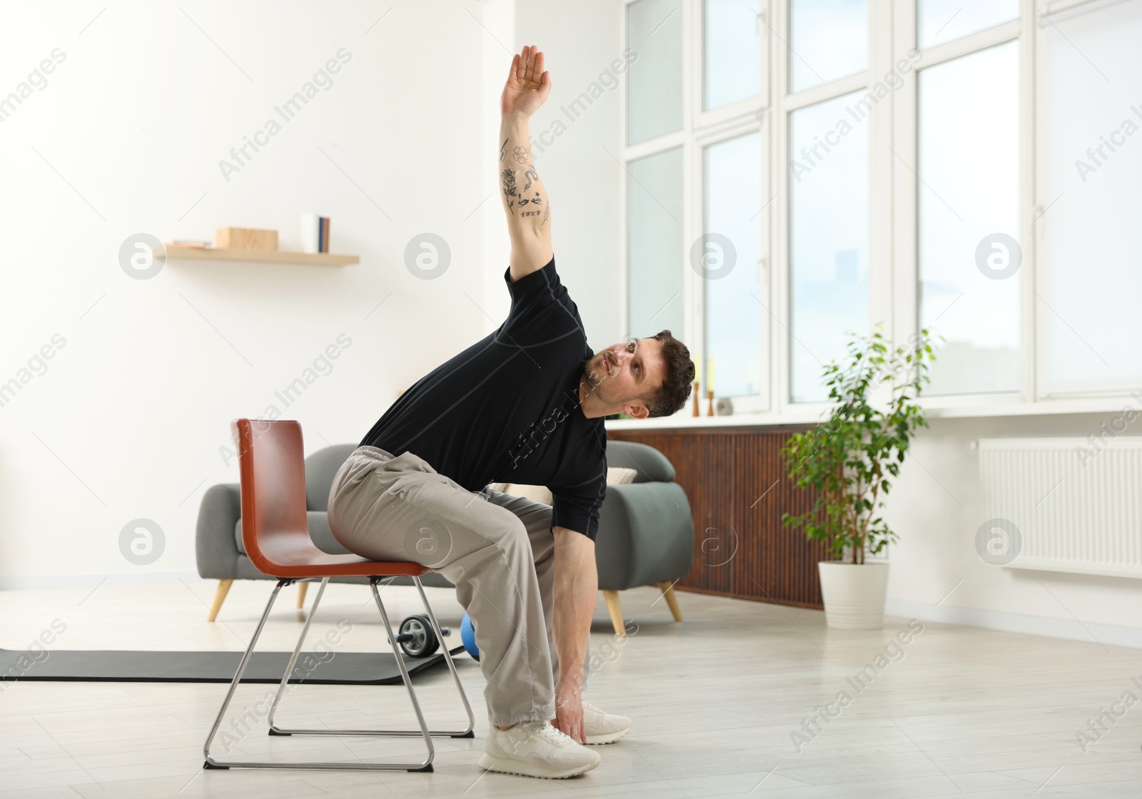Handsome man exercising with chair at home Photo of Handsome man exercising with chair at home