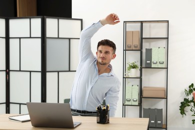 Photo of Handsome man stretching on chair in office