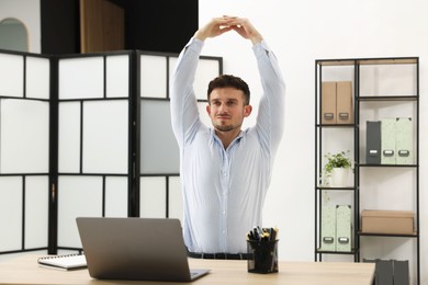Photo of Handsome man stretching on chair in office