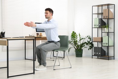 Photo of Handsome man stretching on chair in office