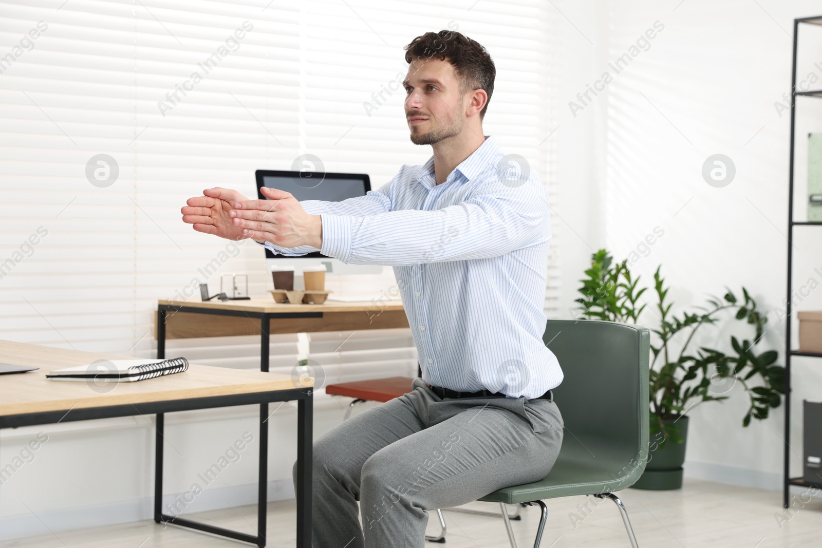 Handsome man stretching on chair in office Photo of Handsome man stretching on chair in office