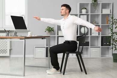 Photo of Handsome man stretching on chair in office