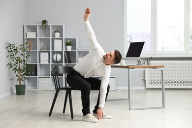 Photo of Handsome man stretching on chair in office