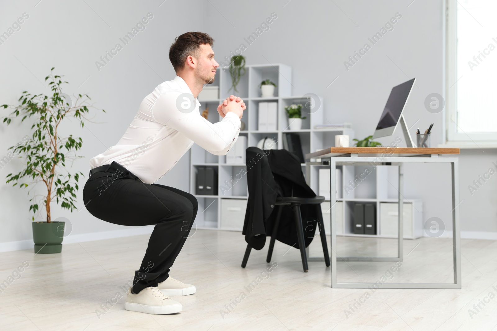 Handsome man doing exercise near desk in office Photo of Handsome man doing exercise near desk in office