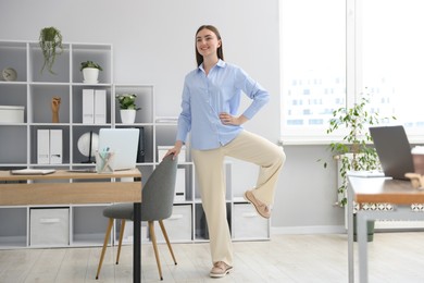 Photo of Beautiful woman exercising with chair in office