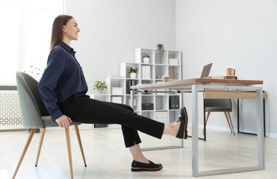 Photo of Beautiful woman exercising with chair in office