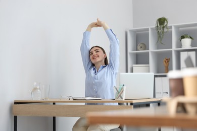 Photo of Beautiful woman stretching on chair in office