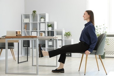 Photo of Beautiful woman exercising with chair in office