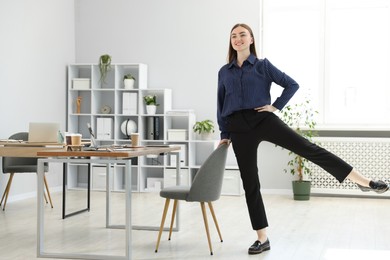Photo of Beautiful woman exercising with chair in office