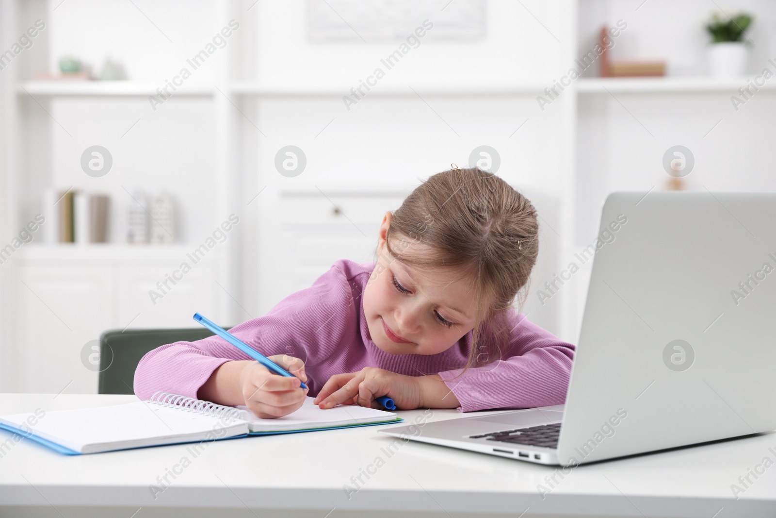 Little girl doing homework at table indoors Photo of Little girl doing homework at table indoors