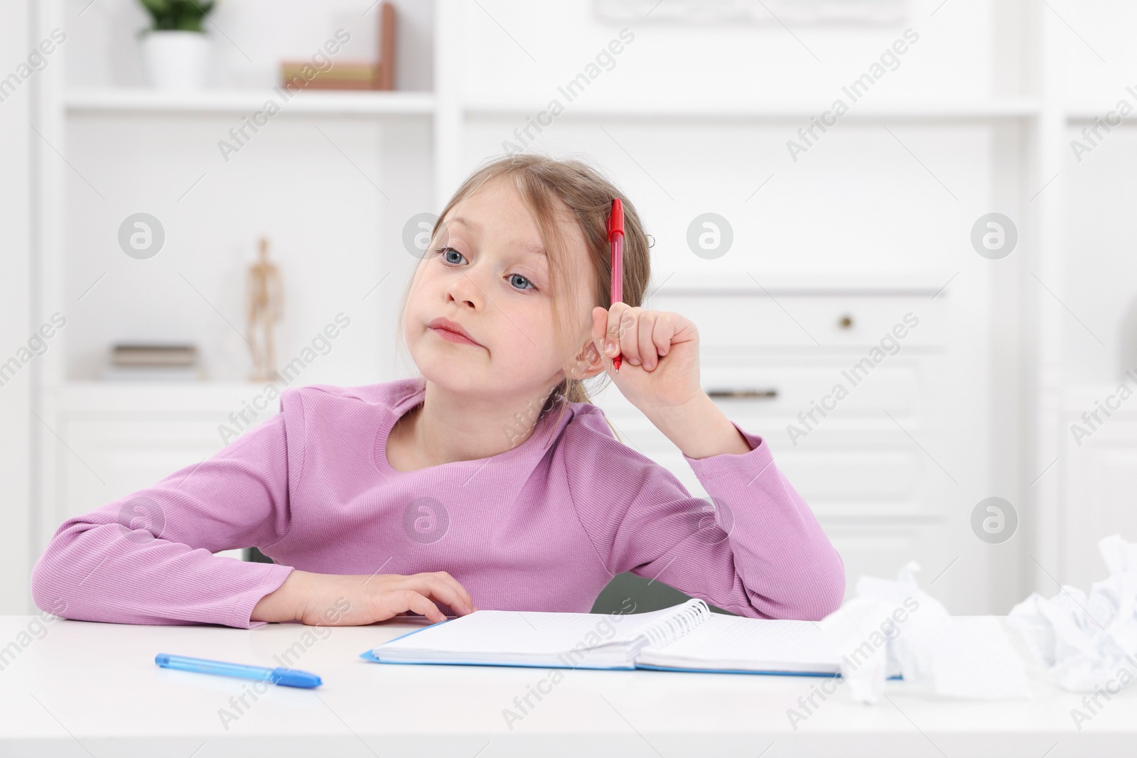 Little girl doing homework at table indoors, space for text Photo of Little girl doing homework at table indoors, space for text