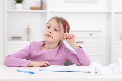 Photo of Little girl doing homework at table indoors, space for text