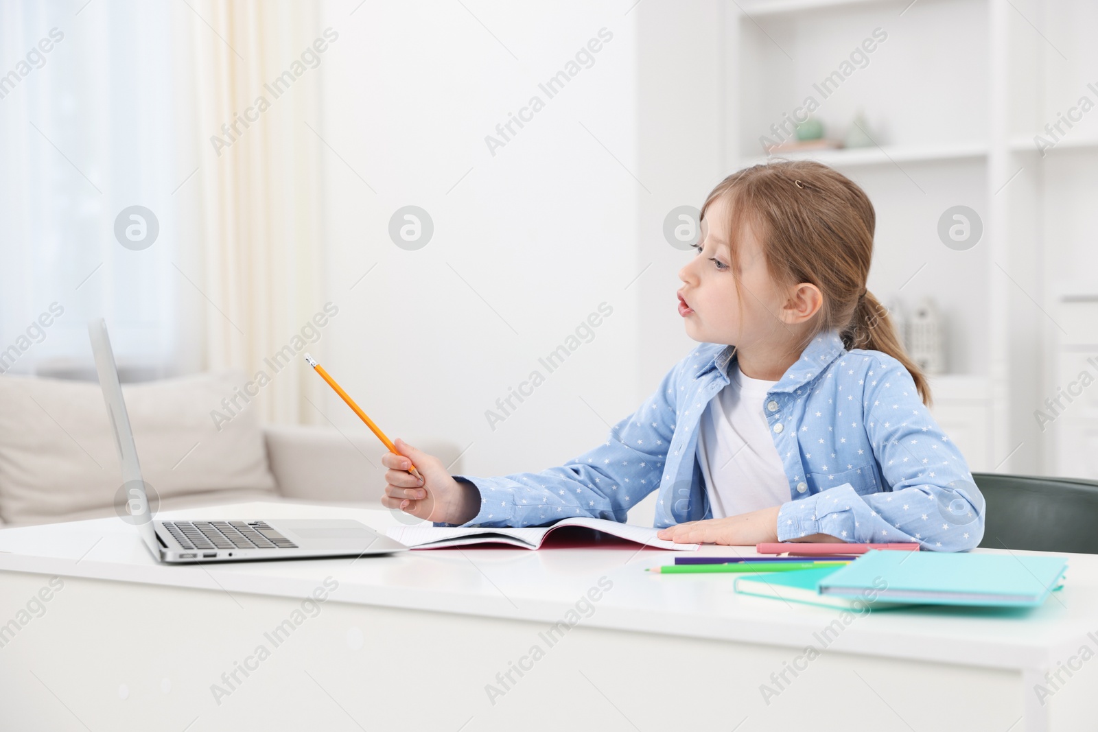 Little girl doing homework at table indoors Photo of Little girl doing homework at table indoors