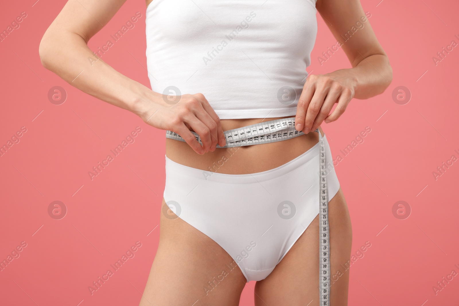 Woman with slim body and measuring tape on pink background, closeup Photo of Woman with slim body and measuring tape on pink background, closeup