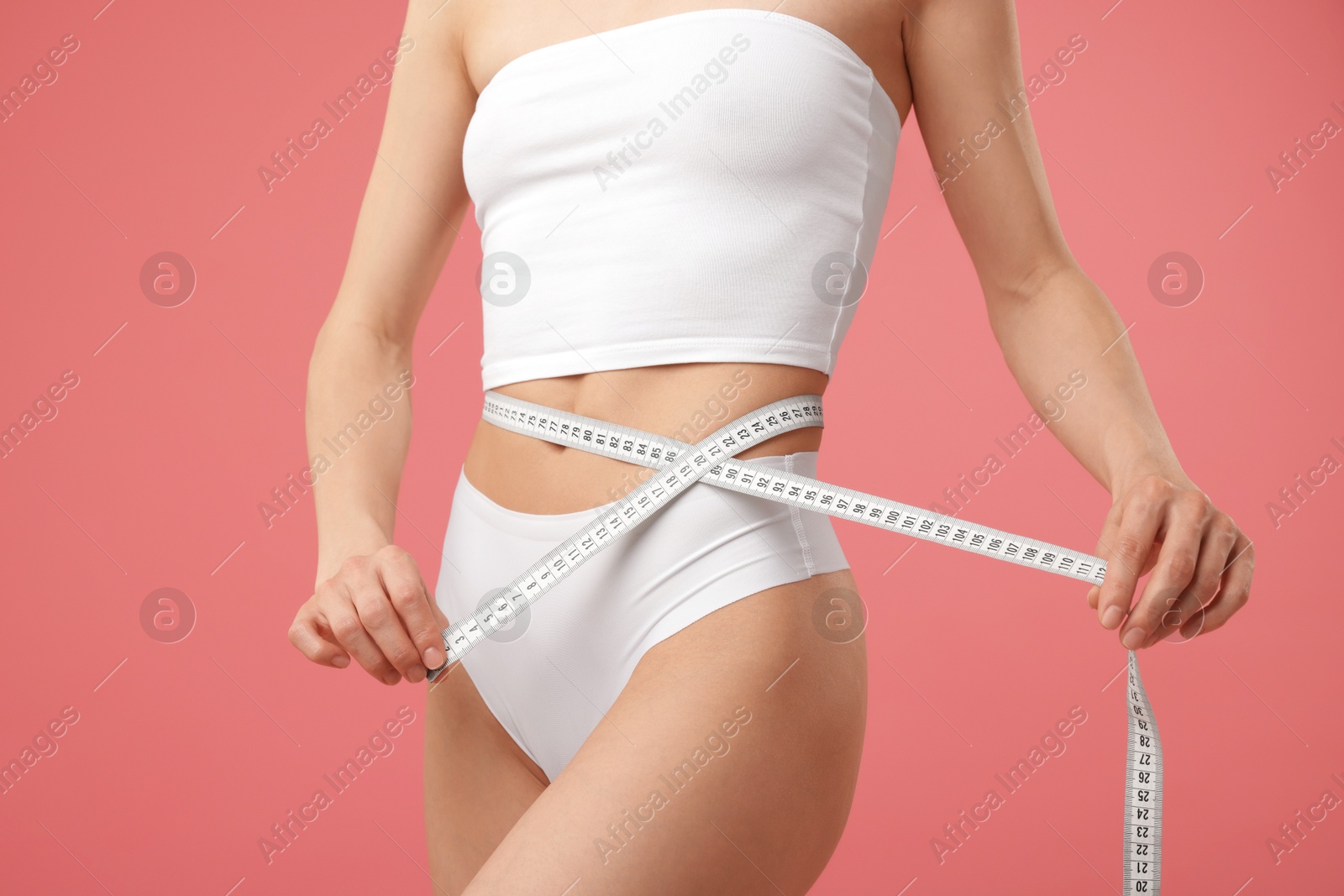 Woman with slim body and measuring tape on pink background, closeup Photo of Woman with slim body and measuring tape on pink background, closeup