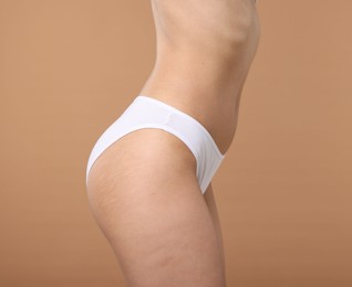 Photo of Woman with perfect slim body on beige background, closeup