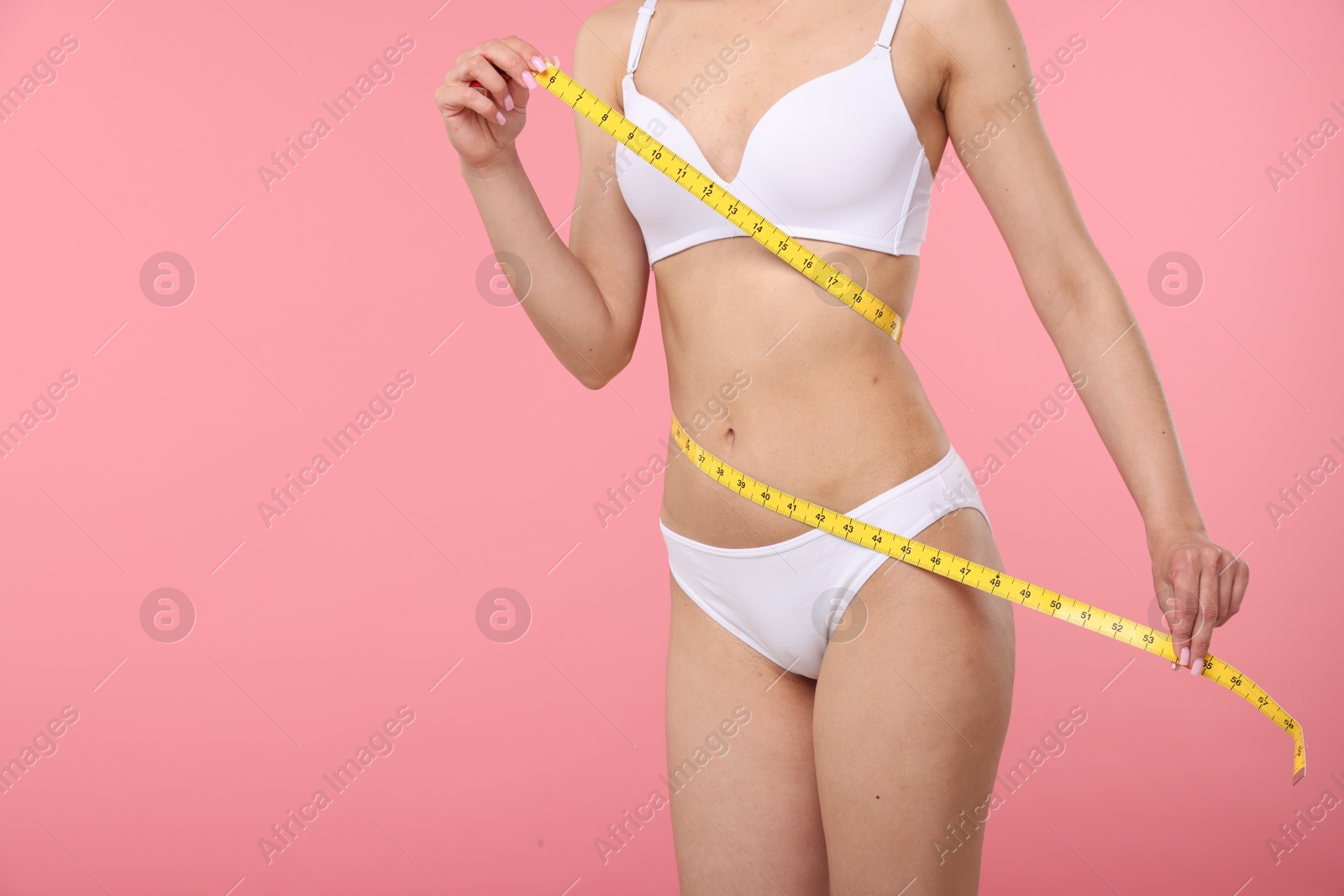 Woman with slim body and measuring tape on pink background, closeup. Space for text Photo of Woman with slim body and measuring tape on pink background, closeup. Space for text