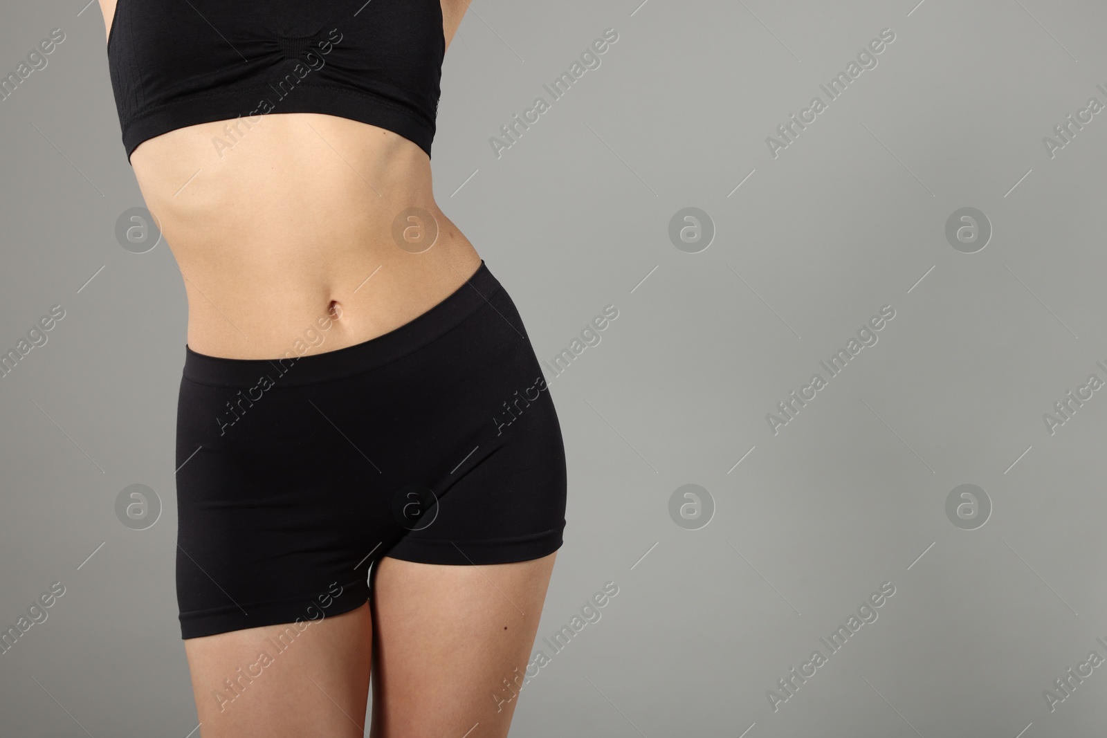Woman with perfect slim body on gray background, closeup. Space for text Photo of Woman with perfect slim body on gray background, closeup. Space for text