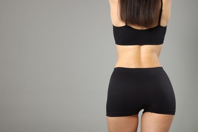 Photo of Woman with perfect slim body on gray background, closeup. Space for text