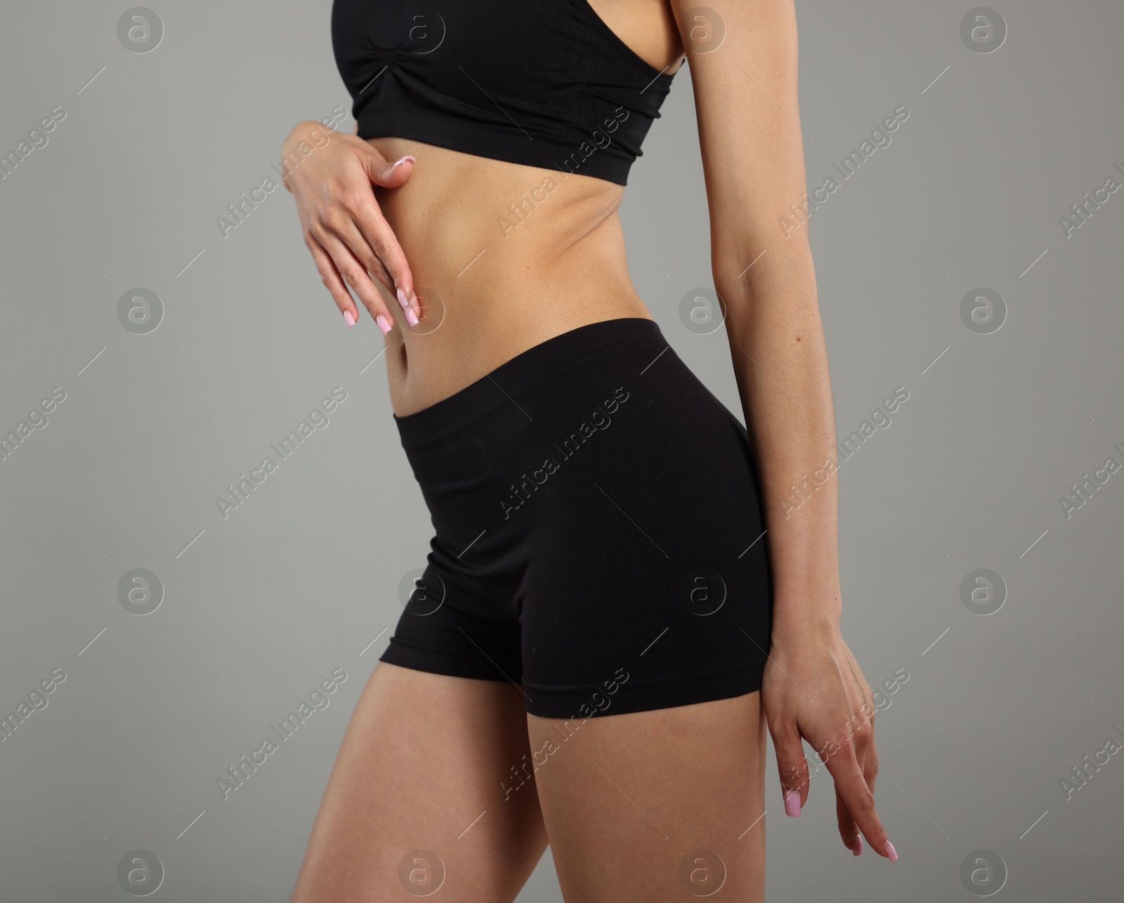 Woman with perfect slim body on gray background, closeup Photo of Woman with perfect slim body on gray background, closeup