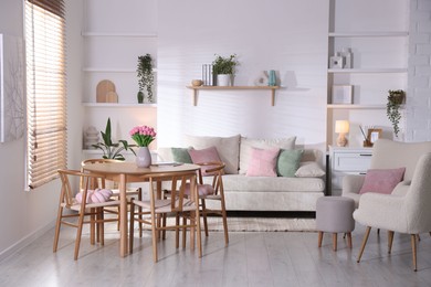 Photo of Stylish dining table with chairs and comfortable sofa in room. Interior design