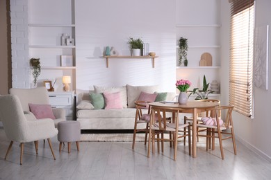 Photo of Stylish dining table with chairs and comfortable sofa in room. Interior design