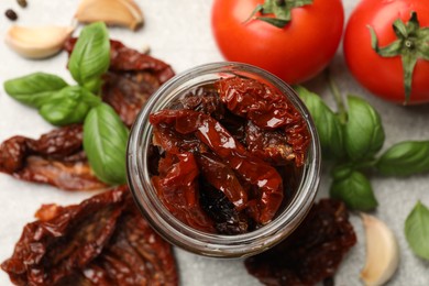 Photo of Delicious sun dried tomatoes, fresh vegetables and spices on grey table, flat lay
