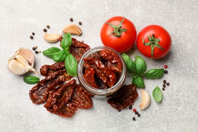 Photo of Delicious sun dried tomatoes, fresh vegetables and spices on grey table, flat lay