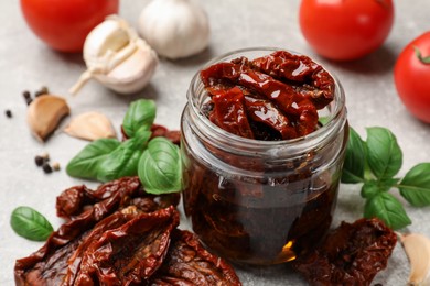 Photo of Delicious sun dried tomatoes, fresh vegetables and spices on grey table, closeup