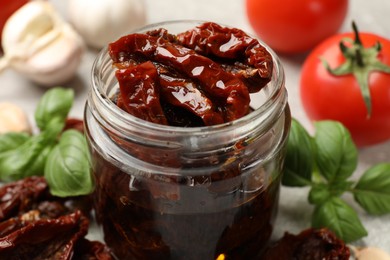 Photo of Delicious sun dried tomatoes, fresh vegetables and spices on table, closeup