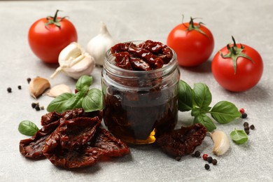 Photo of Delicious sun dried tomatoes, fresh vegetables and spices on grey table, closeup