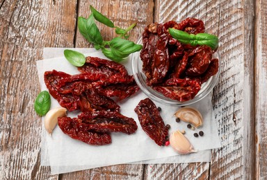 Photo of Delicious sun dried tomatoes and spices on wooden table, flat lay