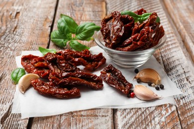 Photo of Delicious sun dried tomatoes and spices on wooden table, closeup