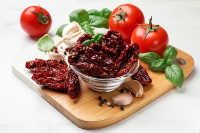 Photo of Delicious sun dried tomatoes, fresh vegetables and spices on white marble table, closeup